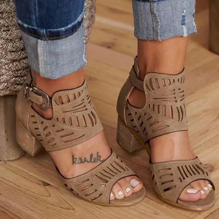 Beige cutout high heel sandals worn with rolled-up denim jeans on wooden floor