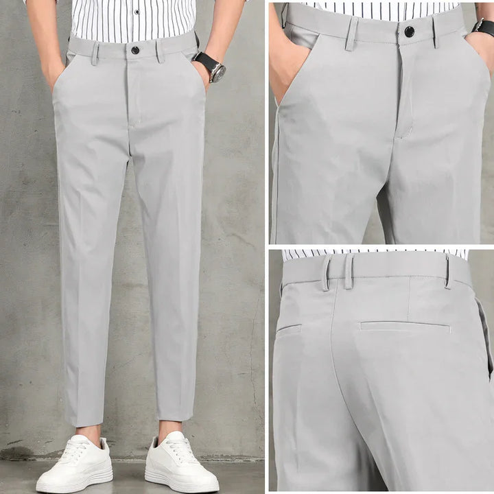 Men's slim fit light gray dress pants with black button, paired with white sneakers and striped shirt