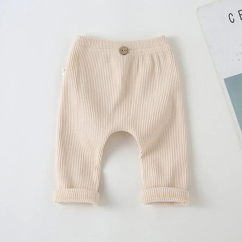 Beige ribbed soft cotton toddler pants with button detail on white background