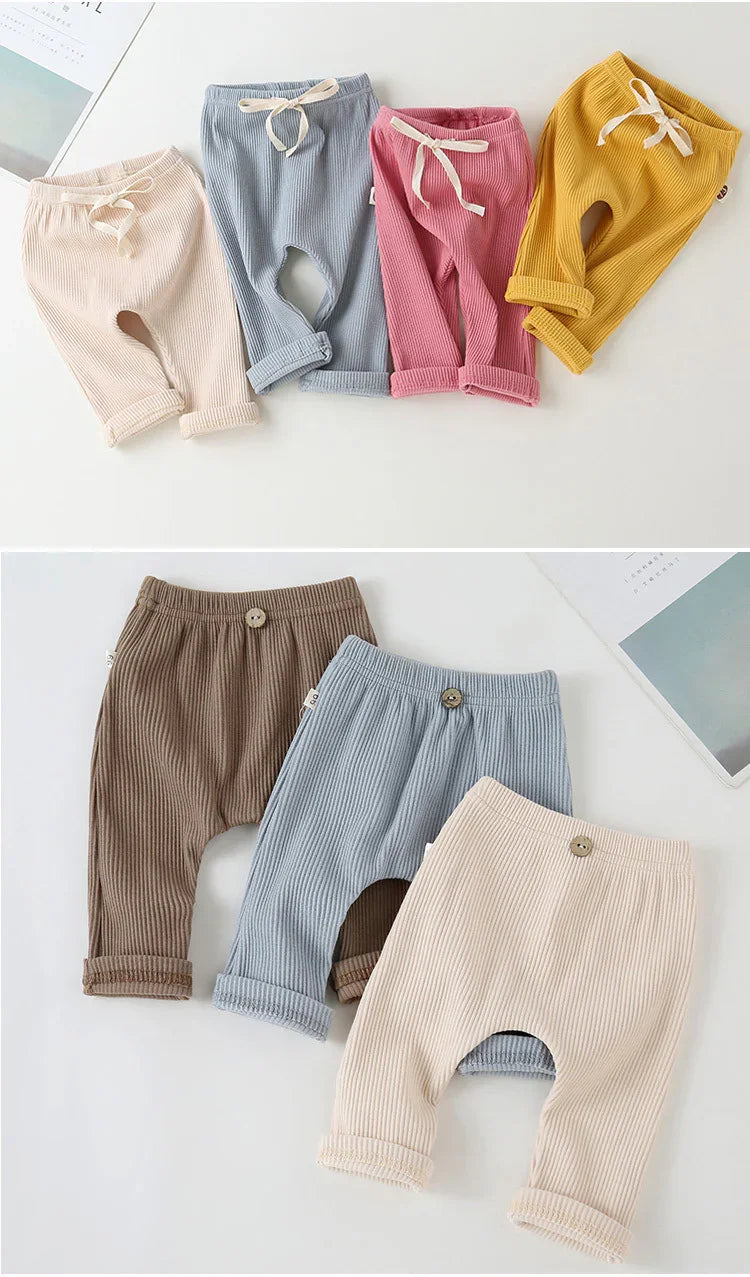 Set of soft ribbed baby pants in beige, blue, pink, yellow, and brown with buttons and drawstrings