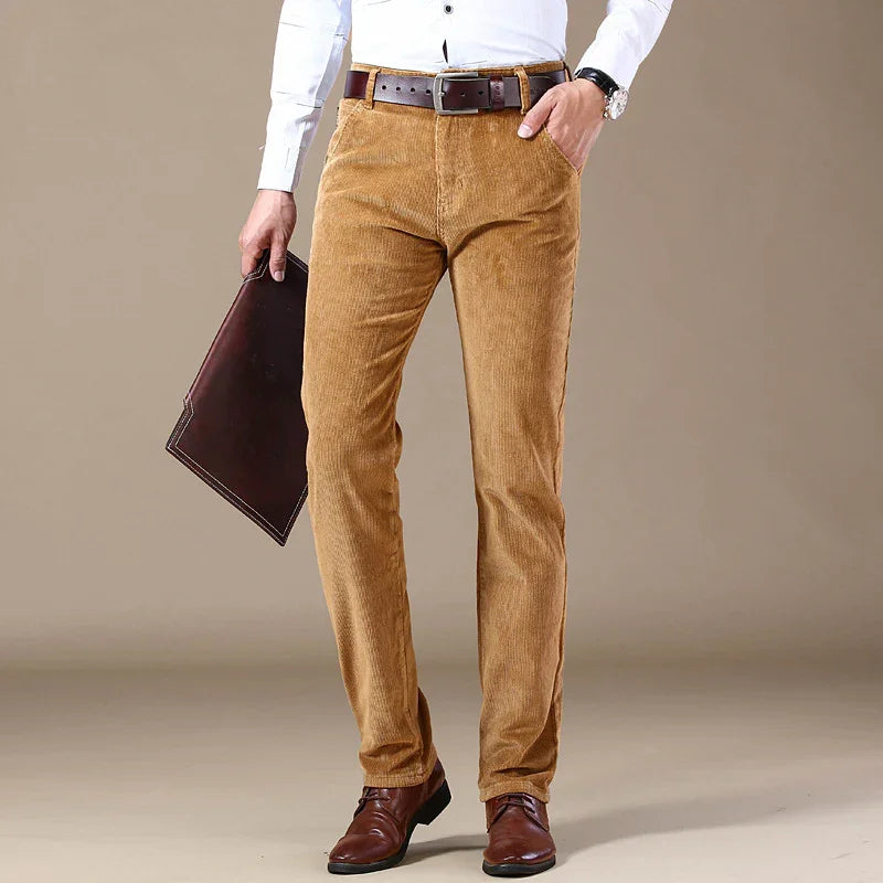 Man wearing tan corduroy pants with brown belt, white shirt, brown leather shoes, holding dark brown leather folder