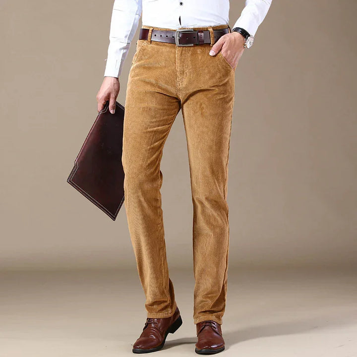 Man wearing tan corduroy pants with brown belt, white shirt, brown leather shoes, holding dark brown leather folder