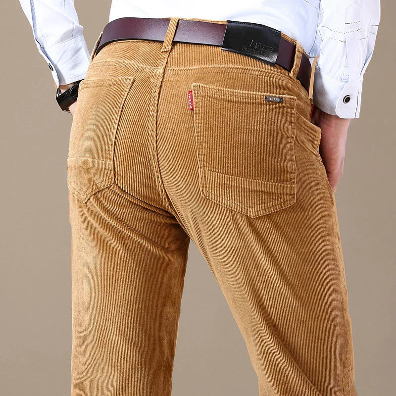 Man wearing tan corduroy jeans with a brown leather belt and white shirt, back view