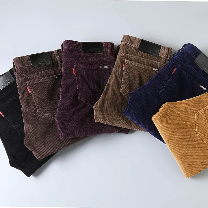 Stack of folded Levi's corduroy pants in black, brown, purple, navy, and mustard colors on a white surface