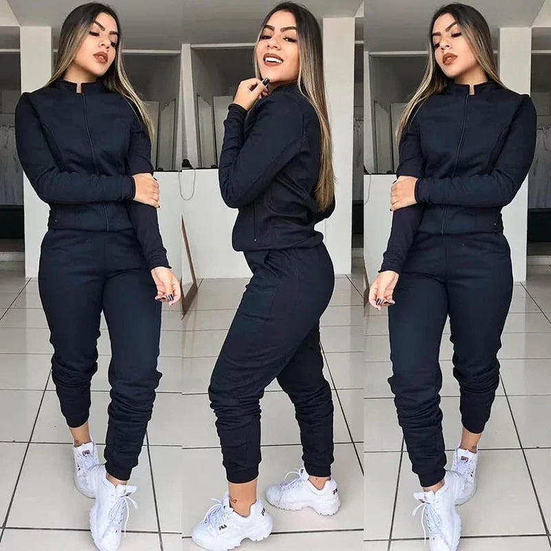 Woman modeling black zip-up jacket and jogger pants with white sneakers in indoor tiled room