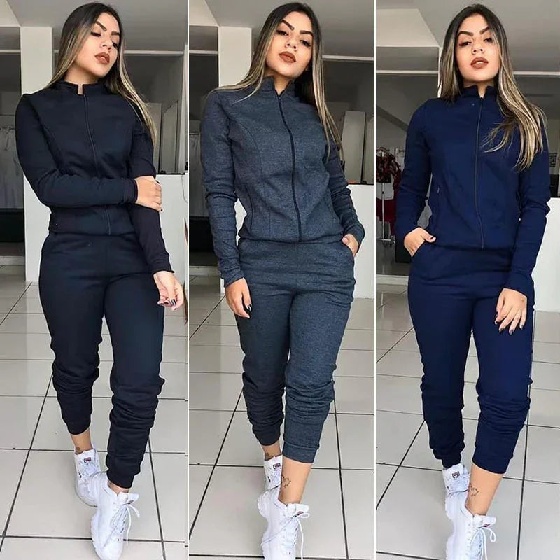 Woman modeling black, dark gray, and navy blue zip-up tracksuits with white sneakers indoors