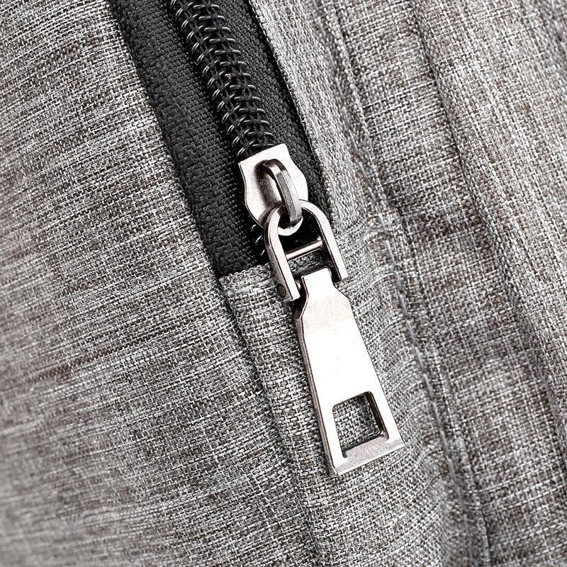 Close-up of silver zipper pull on gray textured fabric with black zipper tape