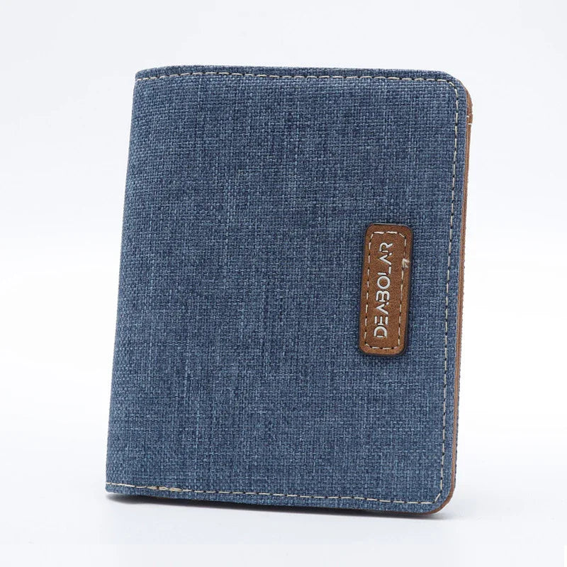 Blue fabric wallet with brown leather logo patch and visible stitching on white background