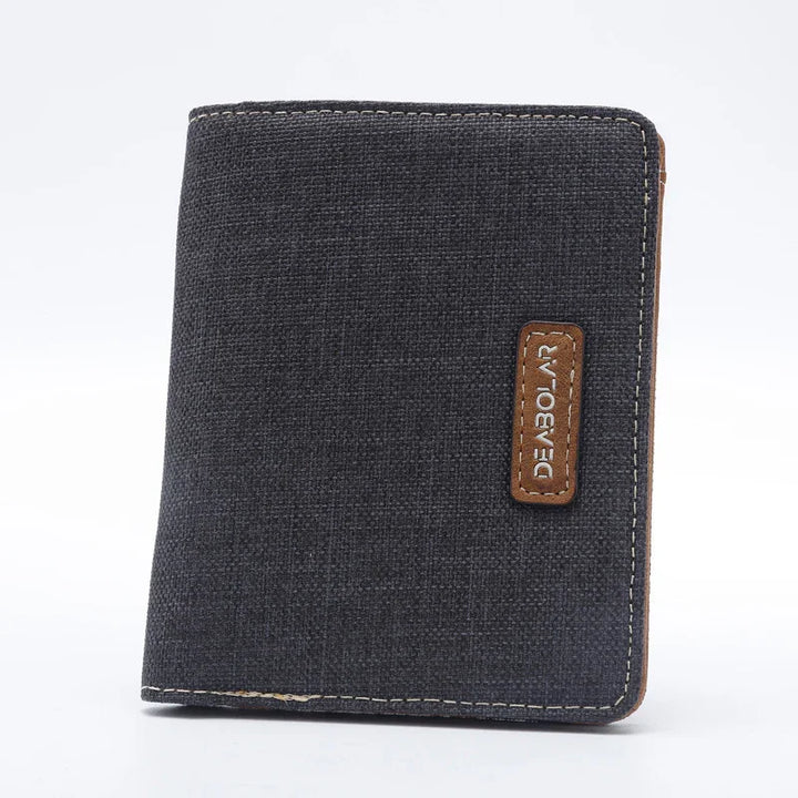 Black canvas wallet with brown leather patch and white stitching on a white background