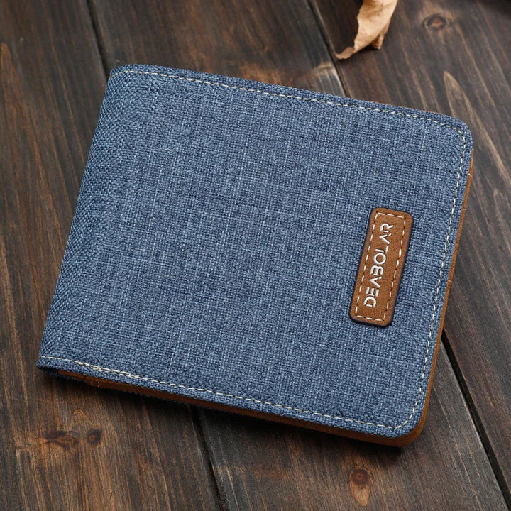 Blue fabric wallet with brown leather patch labeled DEABOLAR on a dark wooden surface