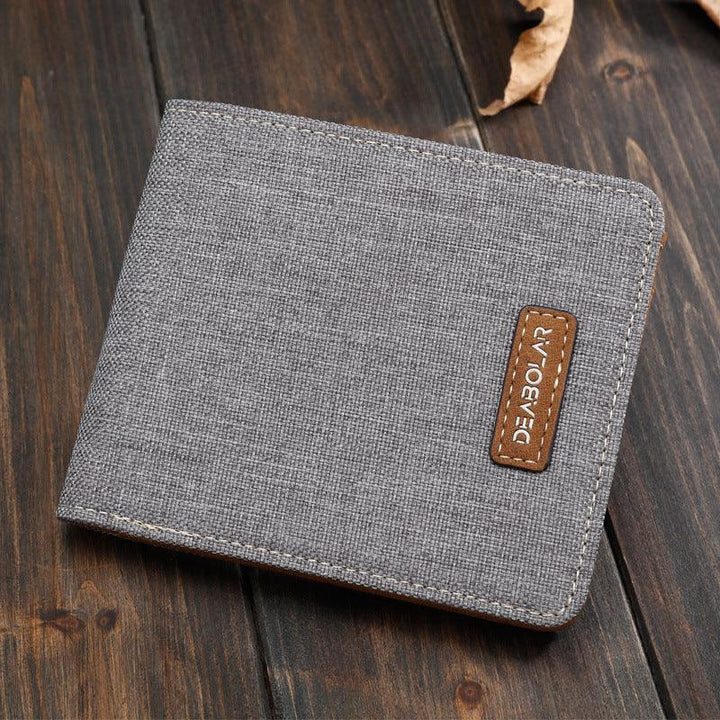 Gray fabric men's wallet with brown leather logo patch on wooden background