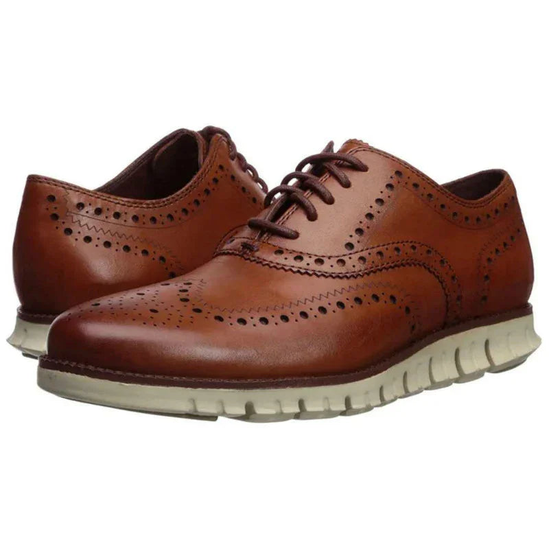 Brown leather brogue wingtip shoes with white rubber sole and decorative perforations