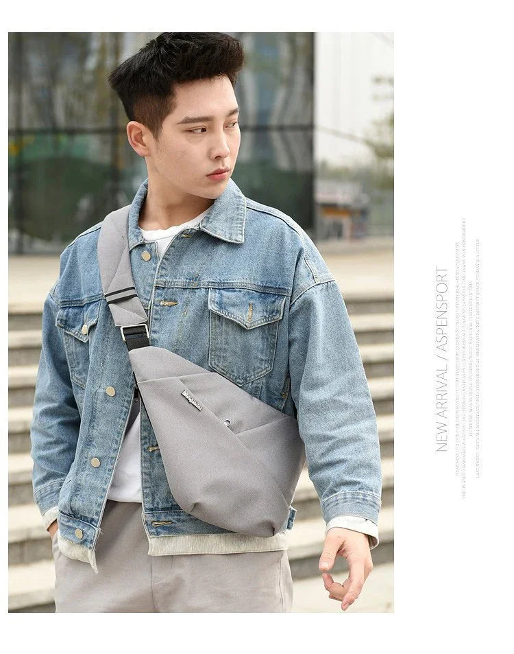 Young man wearing a blue denim jacket and gray crossbody bag outdoors on urban steps