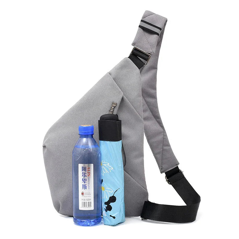 Gray triangular crossbody bag with black adjustable strap, next to a blue water bottle and folded blue floral umbrella