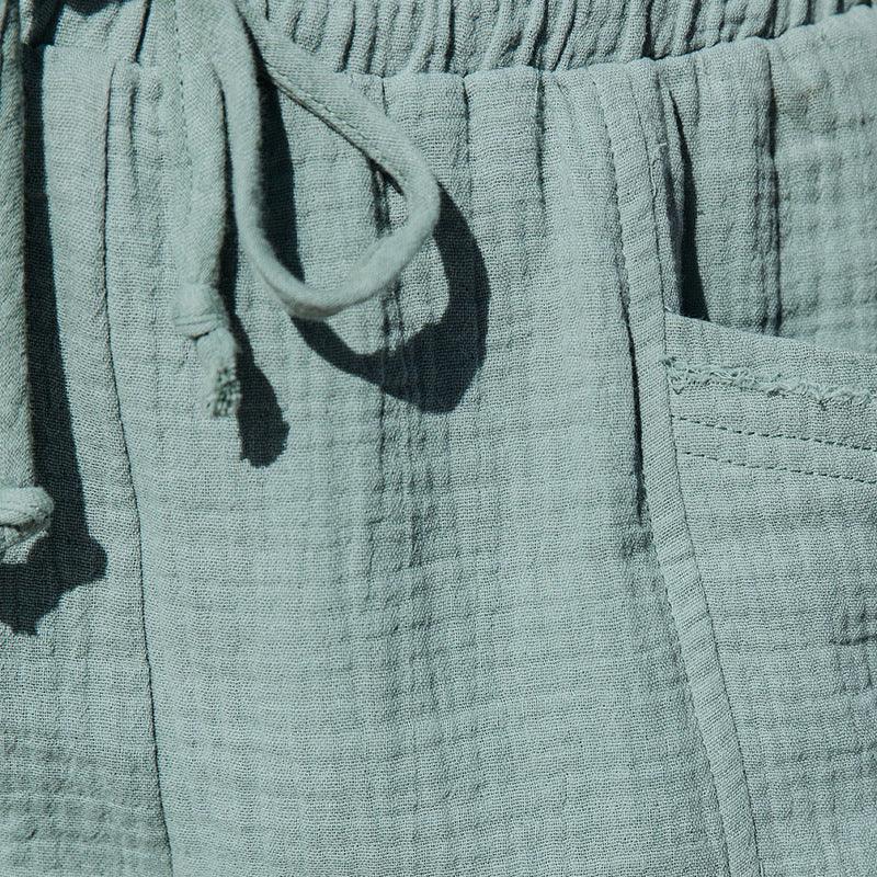Close-up of light blue textured fabric pants with drawstring and visible side pocket stitching