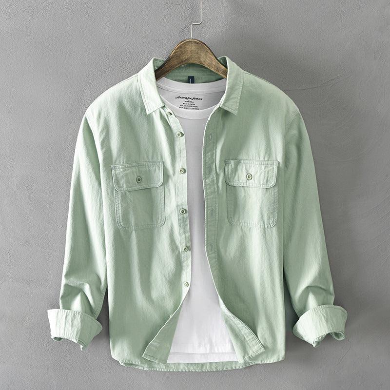 Light green casual men's shirt with chest pockets layered over white t-shirt on wooden hanger