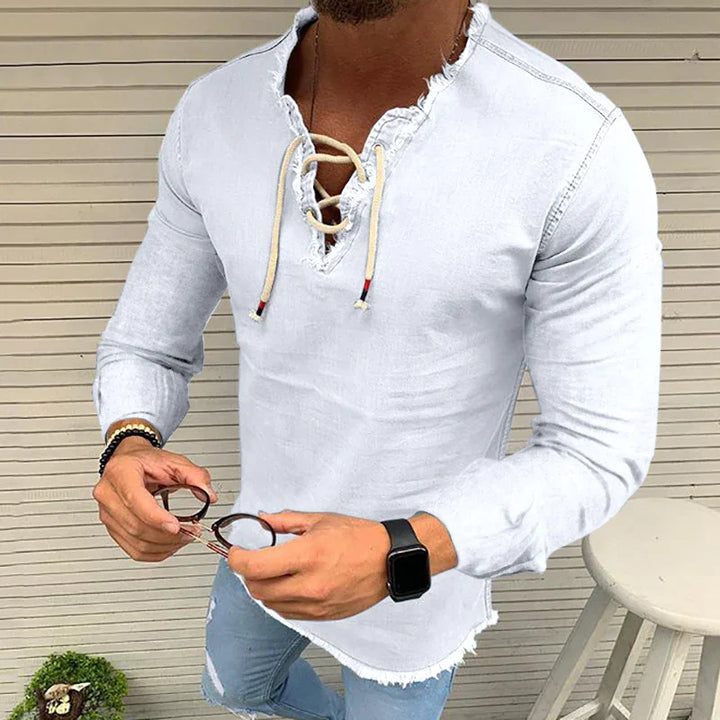 Man wearing white distressed lace-up long sleeve shirt with frayed edges and ripped light blue jeans