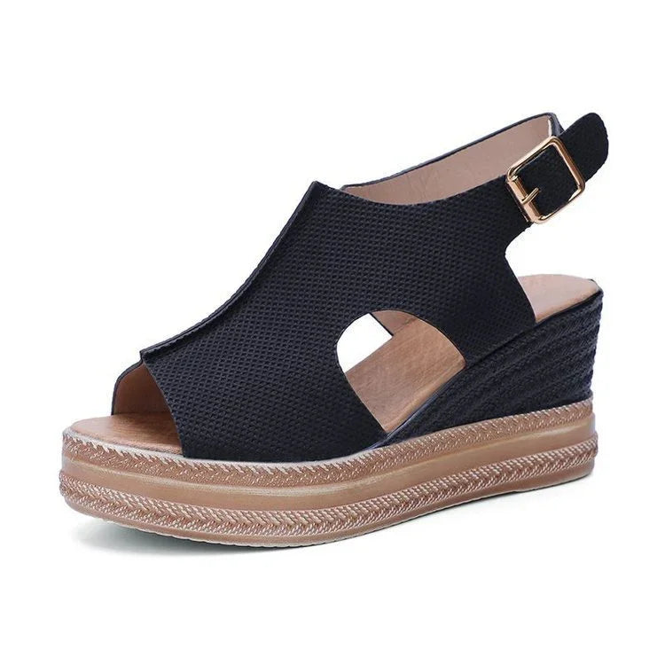 Black wedge espadrille sandal with textured upper, open toe, cut-out sides, and ankle strap with gold buckle