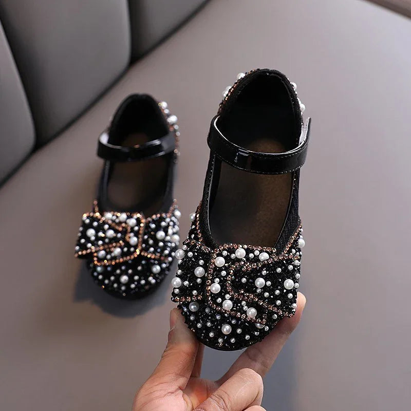 Black toddler Mary Jane shoes embellished with pearls and beads, featuring a bow on the toe