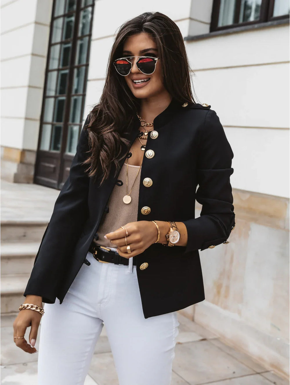 Stylish woman wearing black military jacket with gold buttons, white pants, and sunglasses outdoors