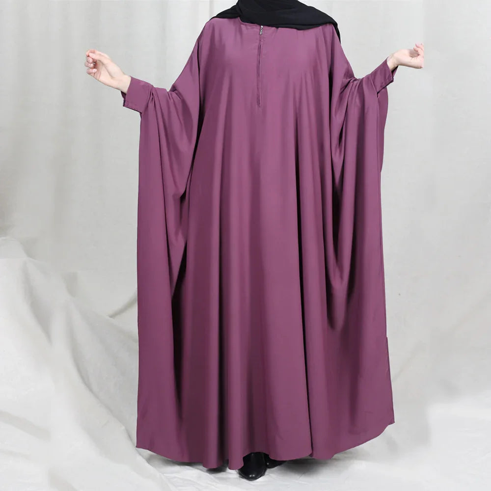 Woman wearing a loose-fitting mauve abaya with wide sleeves and a front zipper detail