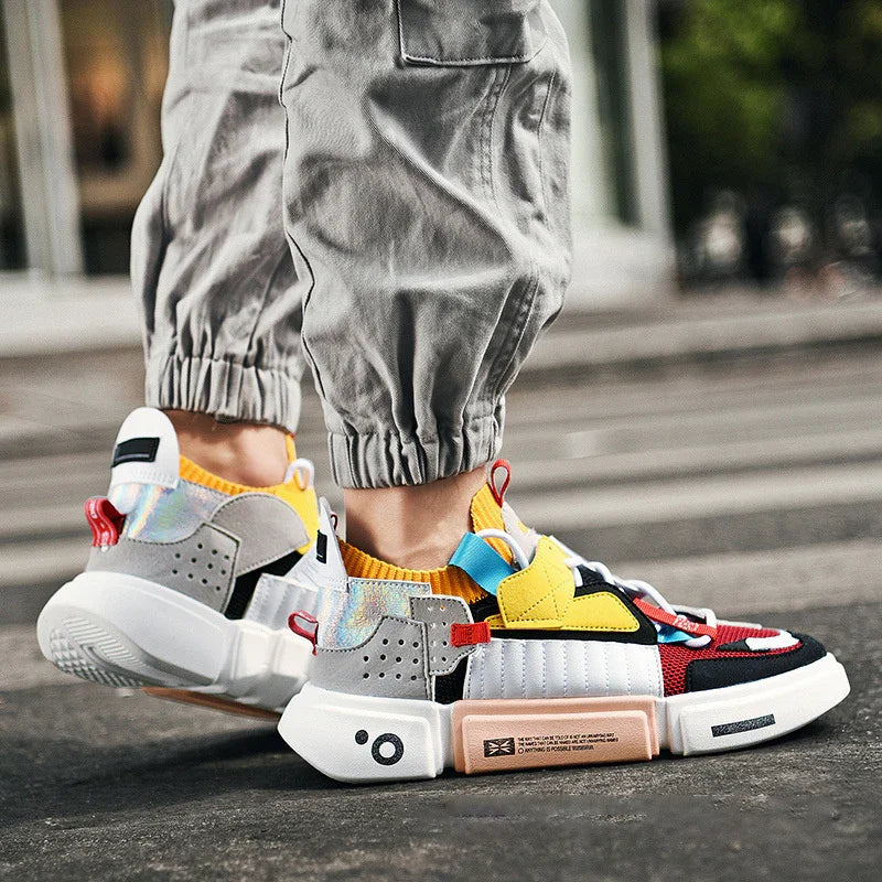 Trendy colorful sneakers with yellow, red, and gray accents worn with cuffed gray pants on urban street
