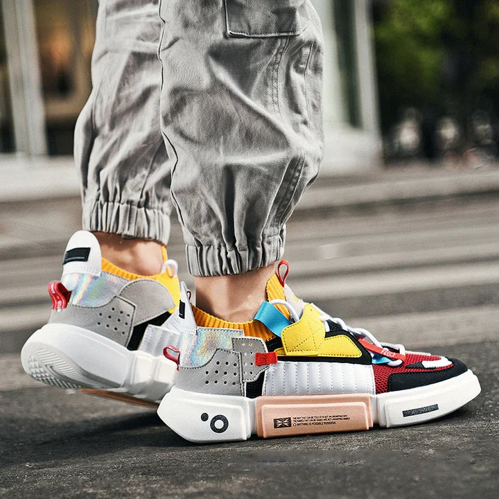 Trendy colorful sneakers with yellow, red, and gray accents worn with cuffed gray pants on urban street