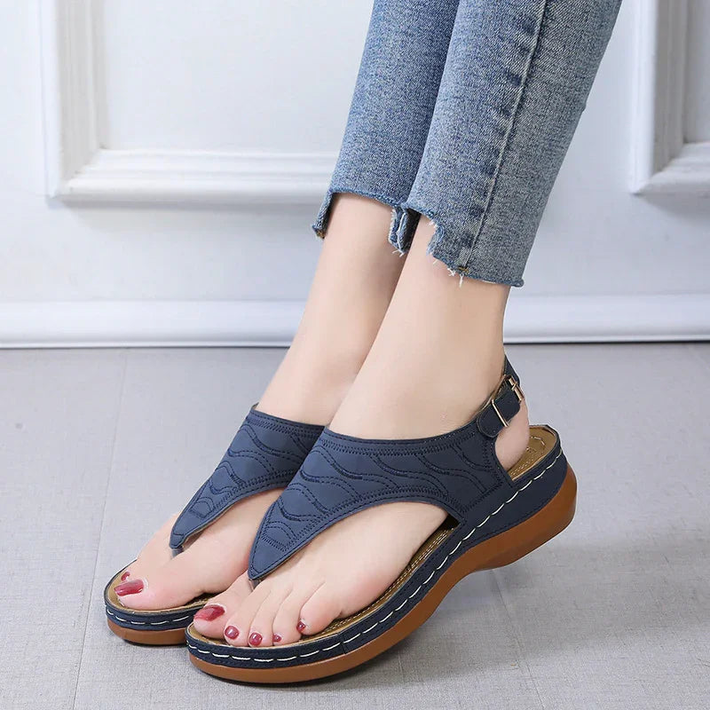 Women's navy blue wedge sandals with ankle strap worn with cropped denim jeans