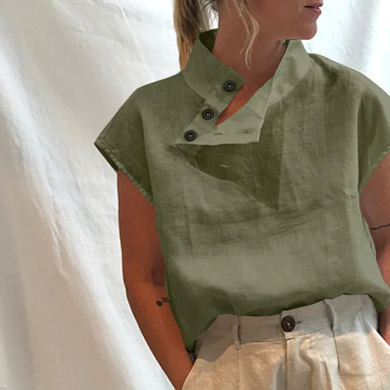 Woman wearing olive green linen short sleeve top with asymmetrical button collar and beige high waist pants