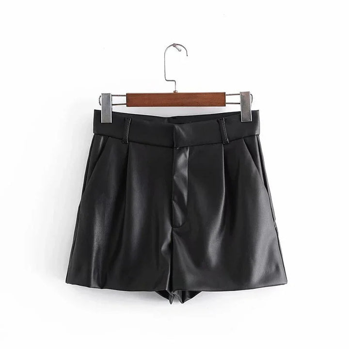 Black faux leather high-waisted pleated shorts on wooden hanger against white background