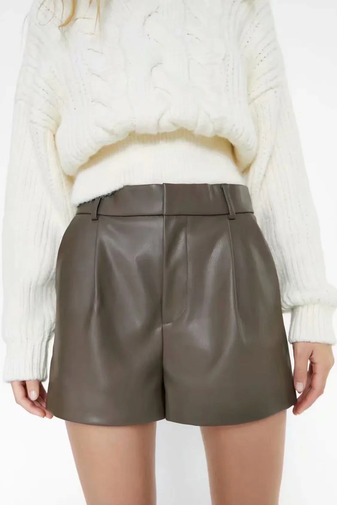 Woman wearing brown leather high-waisted shorts with a white knit sweater