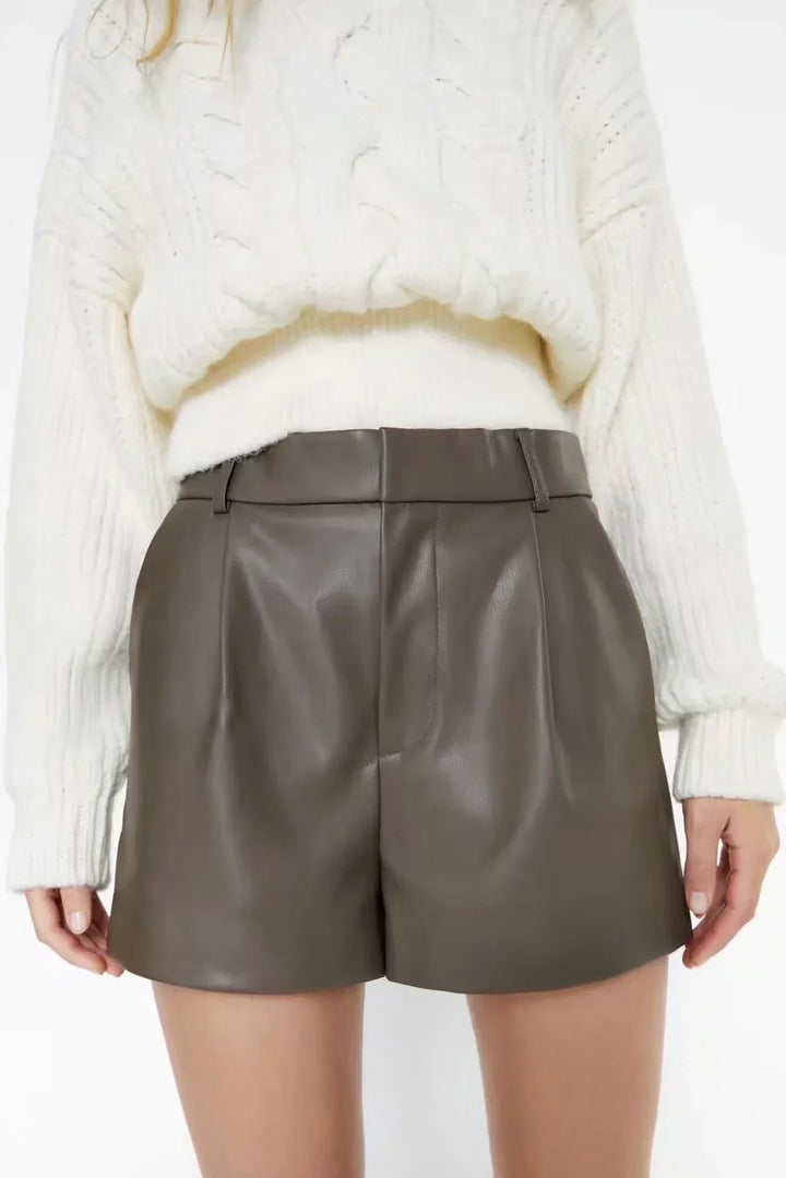 Woman wearing brown leather high-waisted shorts with a white knit sweater