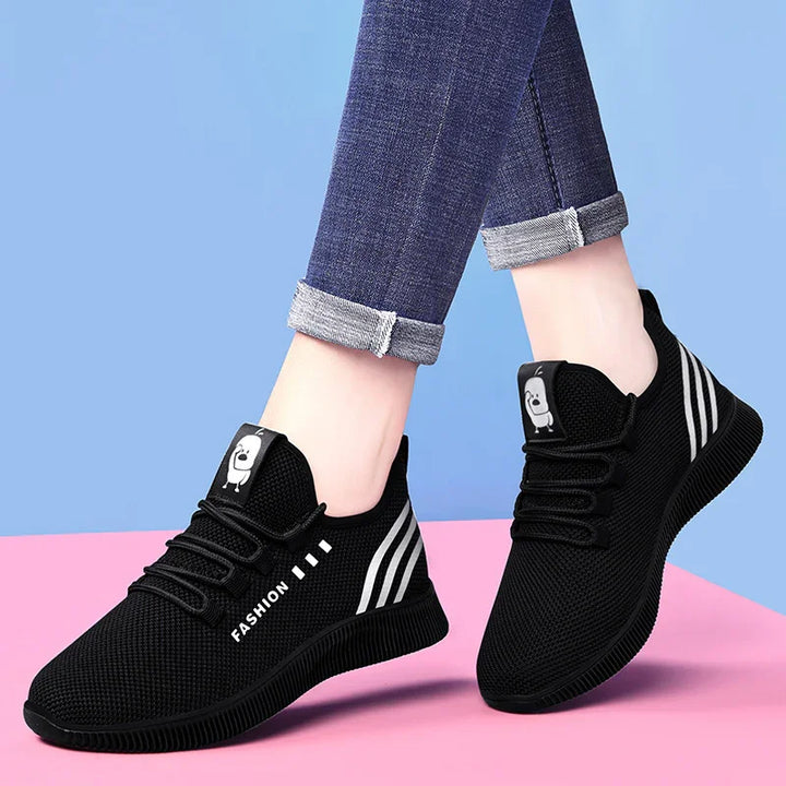 Black mesh casual sneakers with white stripes and cartoon detail, worn with rolled blue jeans