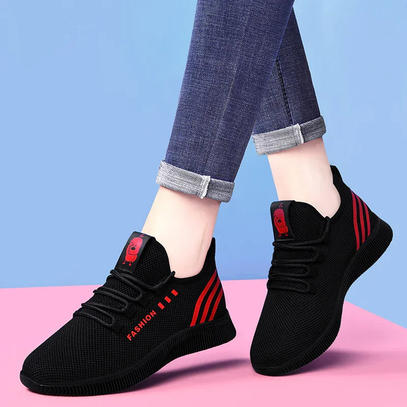 Black mesh sneakers with red stripes and fashion text, worn with rolled-up blue jeans on pink and blue background