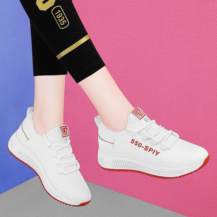 White sporty sneakers with red accents and 550-SPIY text, worn with black leggings against pink and blue background