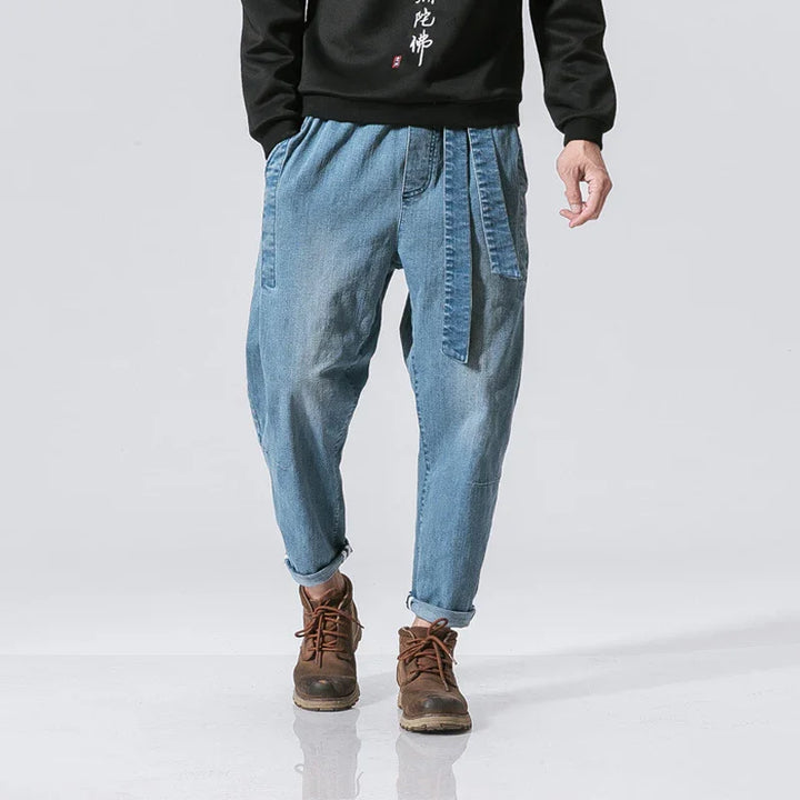 Man wearing casual light blue denim jogger pants with belt loops and brown lace-up boots