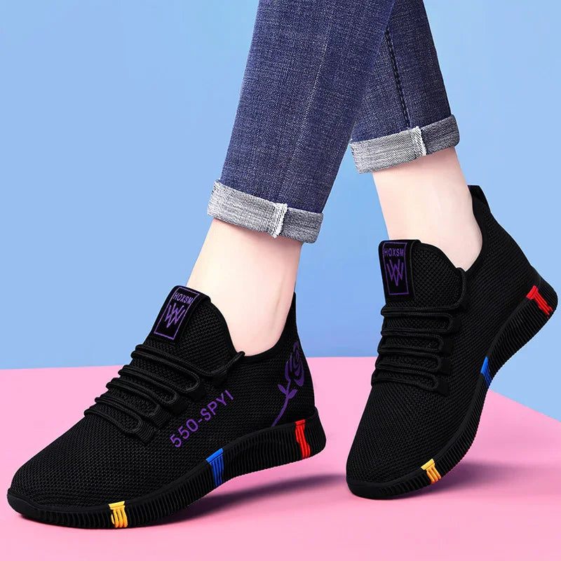 Black casual sneakers with purple details and multicolor sole accents worn with cuffed blue jeans