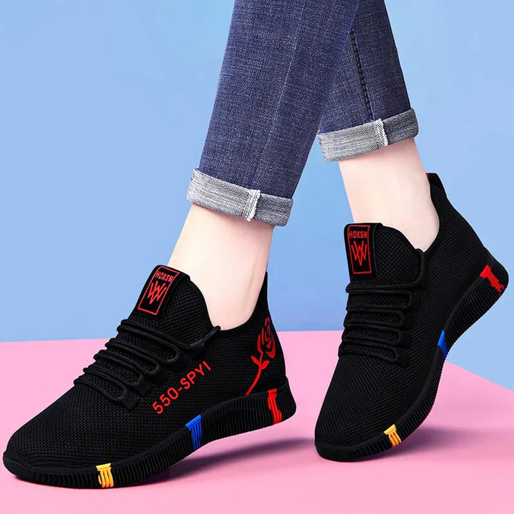 Black casual sneakers with red rose design, 550-SPY1 text, colorful sole accents, worn with rolled jeans