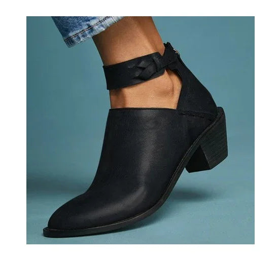 Black leather ankle boot with block heel and braided strap detail, worn with rolled-up jeans