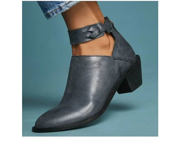 Women's black leather ankle boot with chunky heel and braided ankle strap, worn with rolled-up jeans