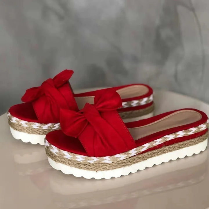 Red platform slide sandals with bow accent and woven jute midsole on white ridged sole