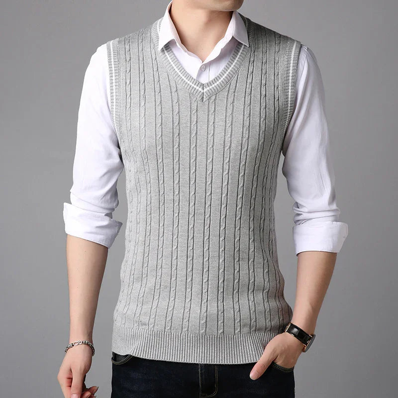 Man wearing light gray cable knit V-neck sweater vest over white dress shirt with rolled sleeves