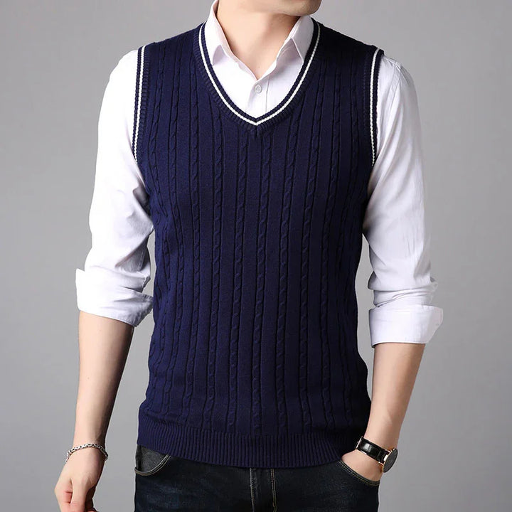 Man wearing navy blue cable knit sleeveless sweater vest over white dress shirt with rolled-up sleeves