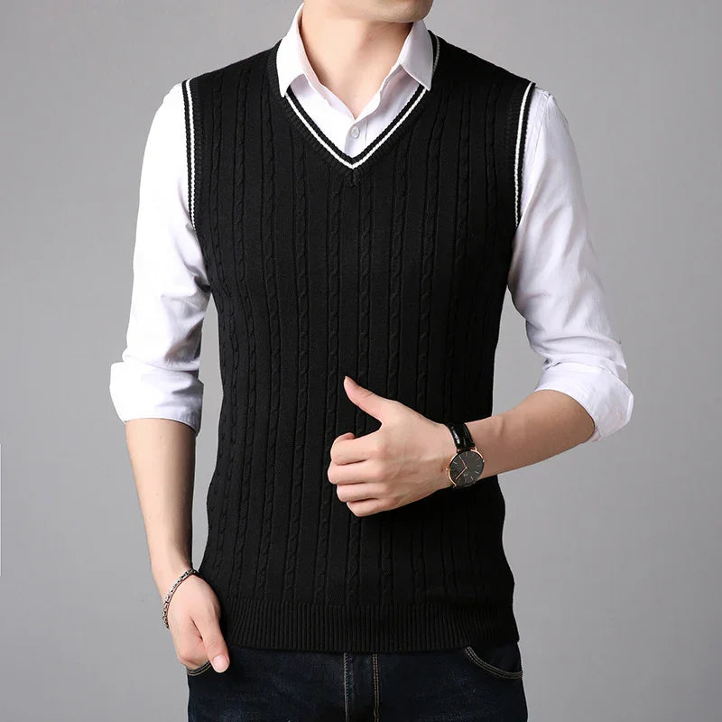 Man wearing black cable knit sleeveless sweater vest over white dress shirt with rolled sleeves