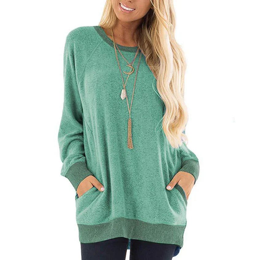 Woman wearing a loose green long-sleeve sweater with pockets and layered necklaces
