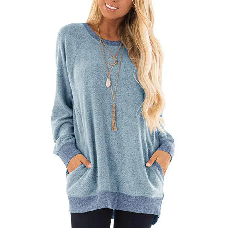 Woman wearing cozy light blue long sleeve sweater with front pockets and layered gold necklaces
