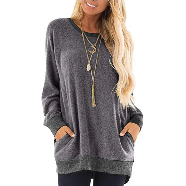 Woman wearing casual loose grey long sleeve sweater with pockets and layered gold necklaces