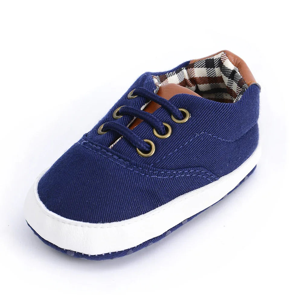 Navy blue baby shoe with white sole, brown accents, and checkered fabric lining