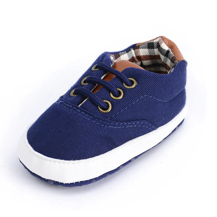 Navy blue baby shoe with white sole, brown accents, and checkered fabric lining