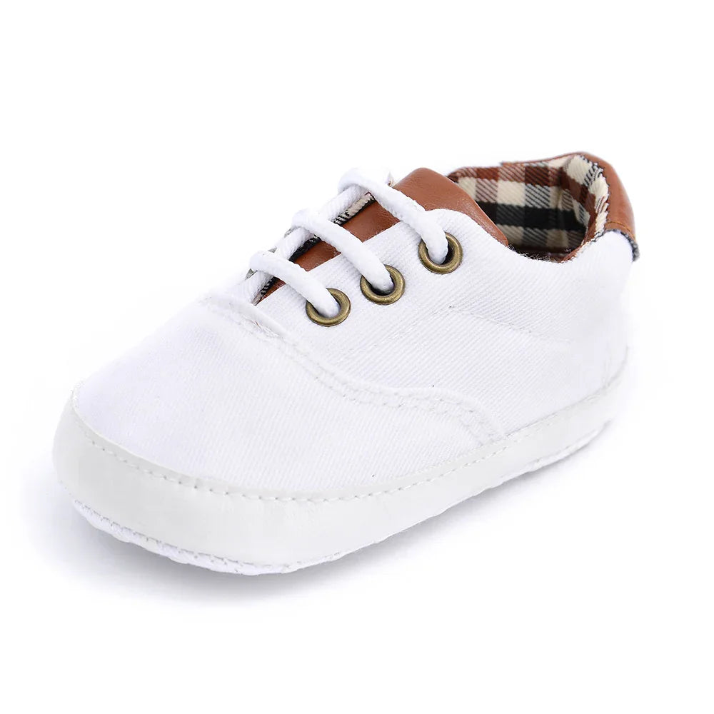 White baby shoe with brown leather accents and plaid inner lining on white background